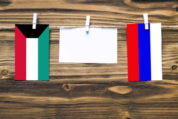 Hanging flags of Kuwait and Russia attached to rope with clothes pins with copy space on white note...