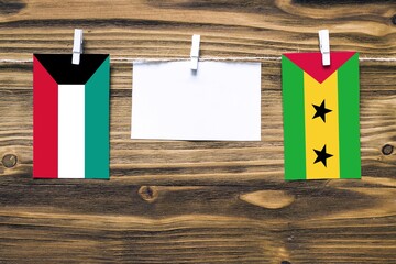 Hanging flags of Kuwait and Sao Tome And Principe attached to rope with clothes pins with copy...