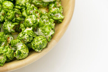 Top view of lush Japanese matcha green tea popcorn in the wooden bowl bulk isolated on white background, Popular snack with favorite movie