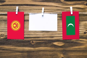 Hanging flags of Kyrgyzstan and Maldives attached to rope with clothes pins with copy space on...