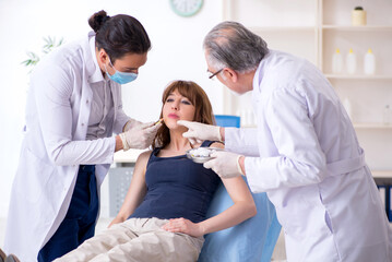 Two male doctors and young woman in plastic surgery concept