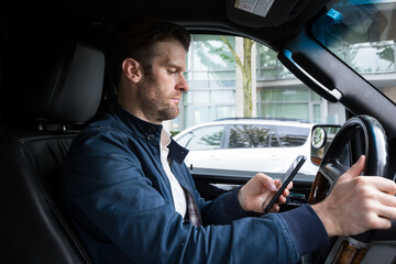 A middle aged caucasian man distracted driving while using a mobile device.