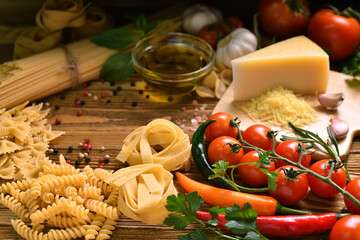 Pasta spaghetti, farfalle with vegetables and spices on wooden table