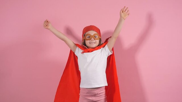 Curly caucasian kid imagine that she is blasting off as superhero, portrait, isolated pink background