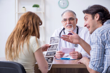 Obraz premium Young couple visiting old male doctor