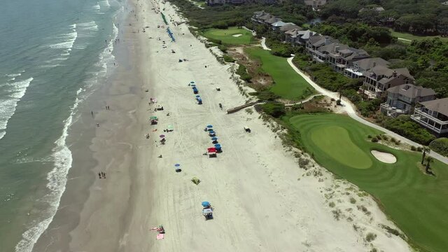 Aerial: People at beach by houses enjoying sunny day during summer weekend - Kiawah Island, SC