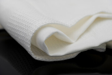 Macro shot texture of folded white towel kitchen fabric isolated on black background