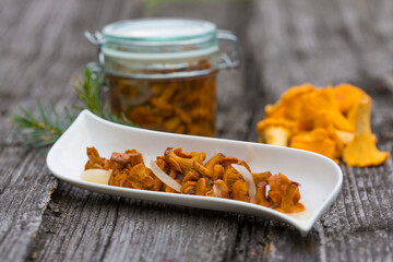 Marinated chanterelle mushrooms in glass jar on rustic background. Selective focus