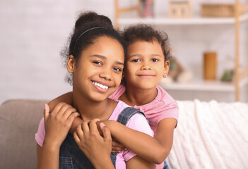 Portrait of african american sisters embracing at home