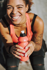 Happy Afro American lady holding bottle of water