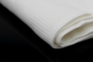 Macro shot texture of folded white towel kitchen fabric isolated on black background