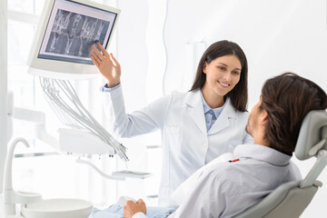 Obraz premium Beautiful female dentist doctor showing her patient x-ray results