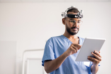 Young medical professional with touchpad scrolling through online data at work