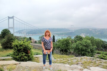 Solo traveling woman with handbag standing with the Istanbul Bosphorus bridge background 