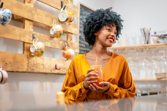 A waitress models serving an orange juice smiling at customers