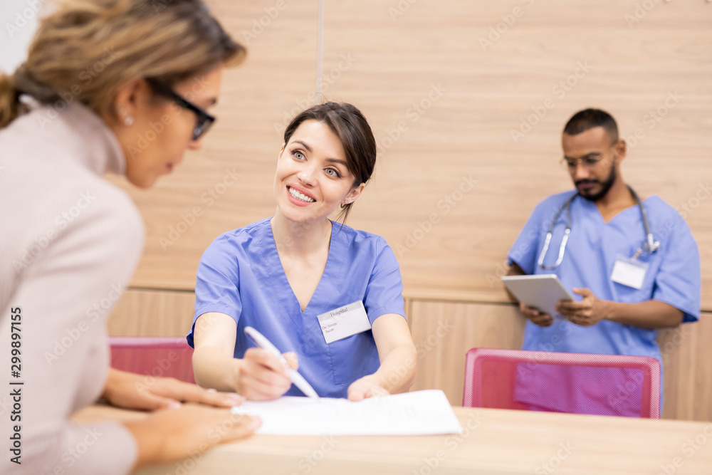 Aufkleber clinician in uniform smiling at patient while pointing at medical document
