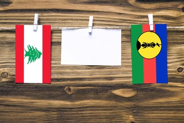 Hanging flags of Lebanon and New Caledonia attached to rope with clothes pins with copy space on...