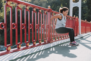Athletic Afro American lady doing exercise on the bridge