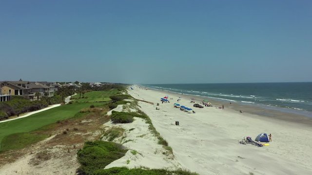Aerial: People at beach by golf courses and houses against clear blue sky on sunny day - Kiawah Island, SC
