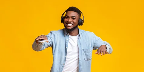 Fotobehang Black guy dancing while listening his favorite music in headphones © Prostock-studio