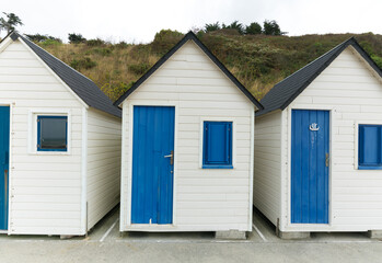 row of small wooden beach cottages on the rocky Normandy coast