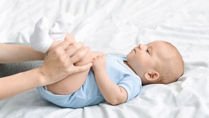 Mom doing gymnastics with her newborn child to relieve constipation.