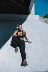 Smiling young lady in headphones resting outdoors