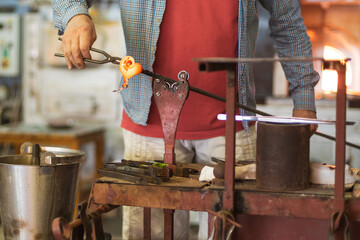 The worker makes a glass ornament in a glassworks
