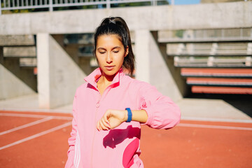 Sportive girl looking at her heart rate monitor watch