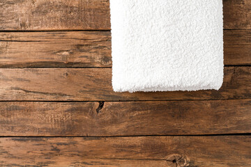 Overhead shot of white spa towel on rustic wooden background with copyspace. Close up