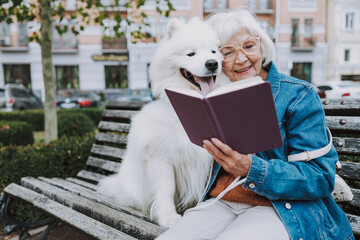 Smiling elderly woman reading book in park
