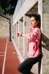 Sport woman leans on column is checking her watch