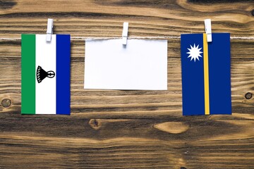 Hanging flags of Lesotho and Nauru attached to rope with clothes pins with copy space on white note...