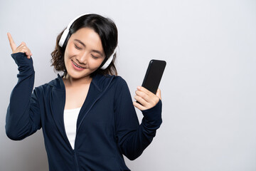 Portrait of a healthy woman use smart phone with headphones listening to music isolated on white background