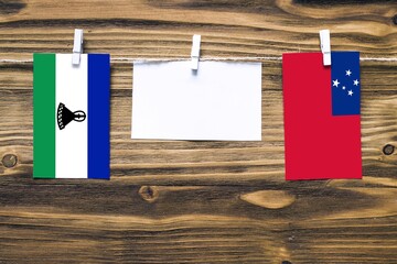Hanging flags of Lesotho and Samoa attached to rope with clothes pins with copy space on white note...