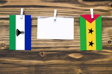 Hanging flags of Lesotho and Sao Tome And Principe attached to rope with clothes pins with copy...