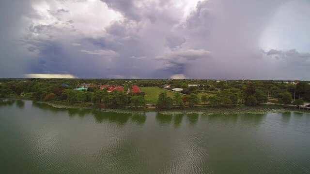 Aerial view above the lake of rain storm with heavy raining above villages and rice paddy fields, Krajub reservoir, Nong Kop District, Ban Pong, Ratchaburi, Thailand.