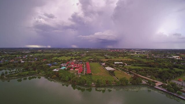 Aerial view above the lake of rain storm with heavy raining above villages and rice paddy fields, Krajub reservoir, Nong Kop District, Ban Pong, Ratchaburi, Thailand.