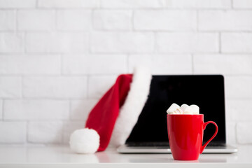 Obraz na płótnie Canvas Christmas advertisement of modern laptop in Santa's hat