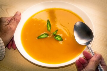 woman holding bowl of soup with spoon