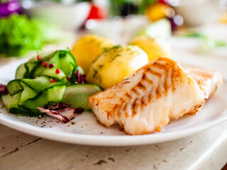 Fried fish with potatoes on white plate