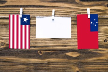 Hanging flags of Liberia and Samoa attached to rope with clothes pins with copy space on white note...