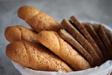 Fresh bread baguette with sesame seeds and slices of rye bread are in the breadbox on the table. Bakery. Flat lay. Close-up, minimalism.