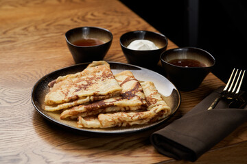 Homemade pancakes with jam, honey and sour cream bowls, close-up