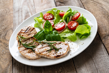 Grilled steaks with vegetable salad on white plate