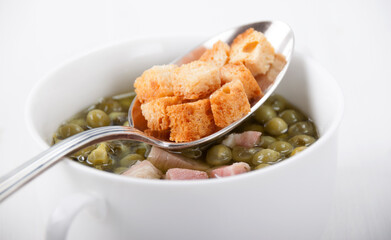 Pea soup with pancetta in a white bowl