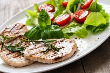 Grilled steaks with vegetable salad on white plate