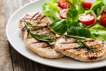 Grilled steaks with vegetable salad on white plate