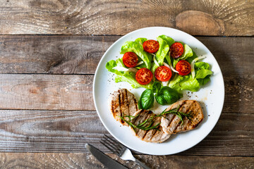 Grilled steaks with vegetable salad on white plate