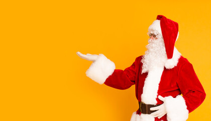 Fototapeta na wymiar Santa Claus pointing at copy space for advertisement on orange